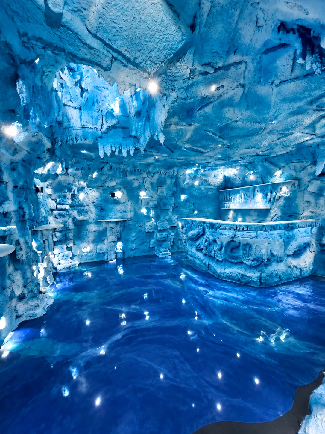 Originalaufnahme der fertiggestellten ARCUM-Icebar mit blauem Licht, Felsstruktur und Theke.