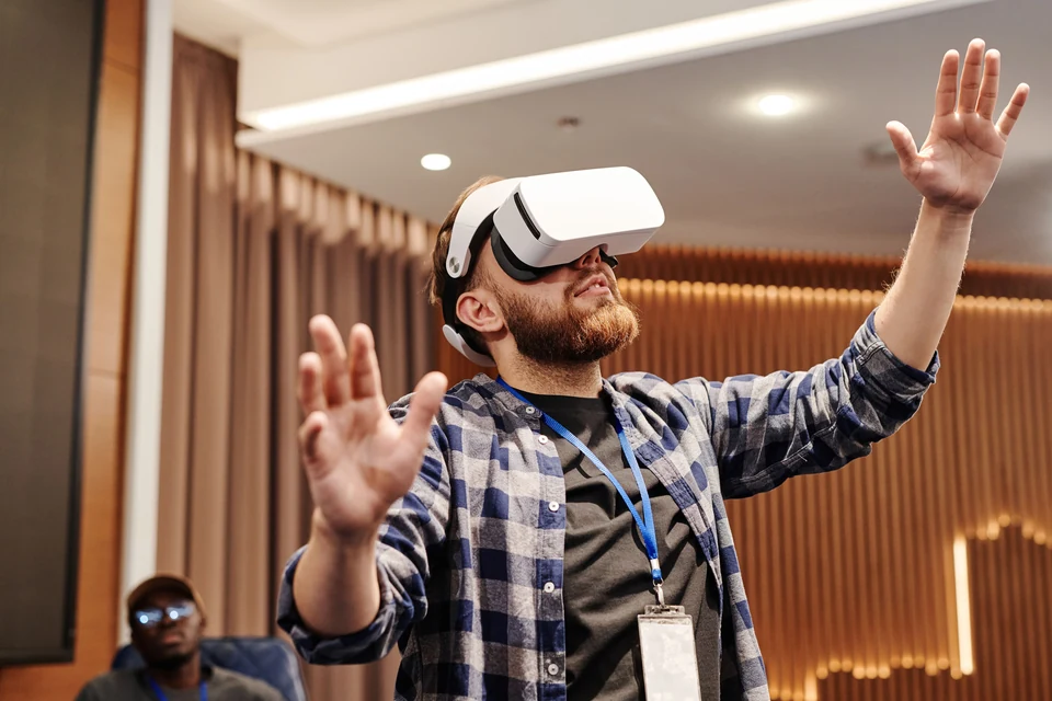 Ein erwachsener Mann trägt eine deutlich sichtbare weiße VR-Brille und hebt seine Hände; keine Aufnahme eines ARCUM-Besuchs.